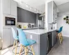 Kitchen with beverage cooler, gray cabinetry, kitchen peninsula, a breakfast bar, and stainless steel fridge