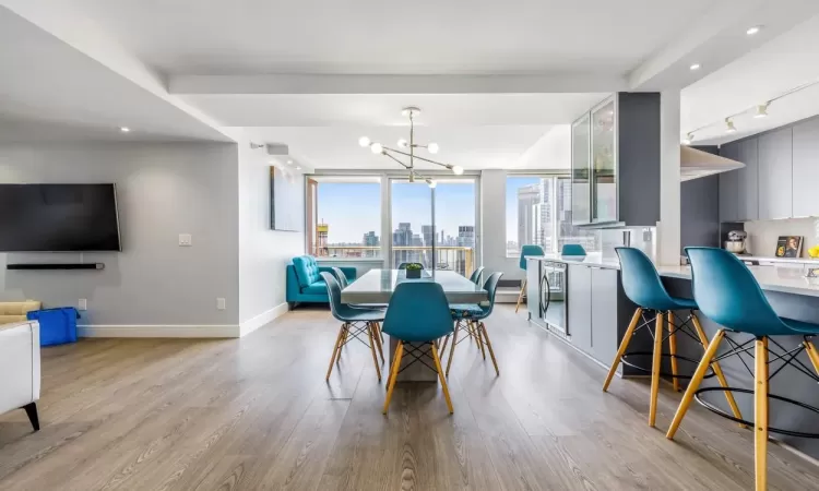 Dining area with light hardwood / wood-style floors, track lighting, and an inviting chandelier