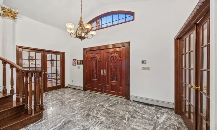 Entryway featuring high vaulted ceiling, an inviting chandelier, french doors, and a baseboard radiator