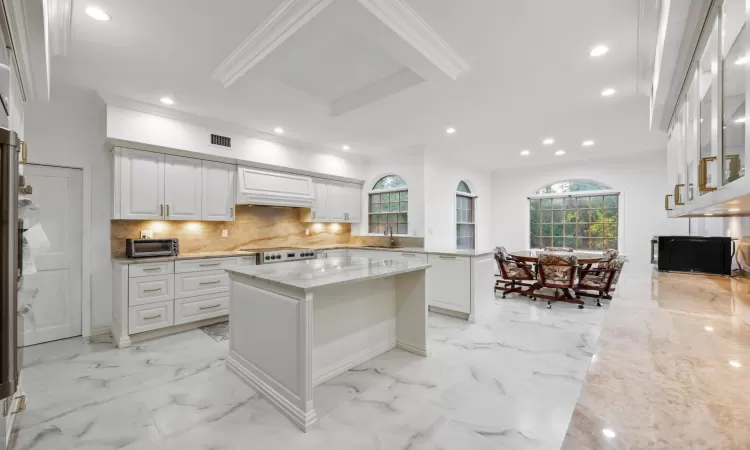 Kitchen with a kitchen island, white cabinetry, range, and light stone counters