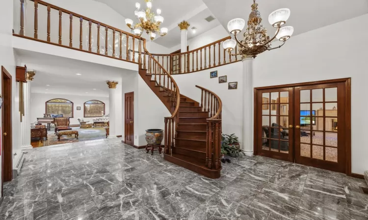 Entrance foyer featuring a towering ceiling, a notable chandelier, and french doors