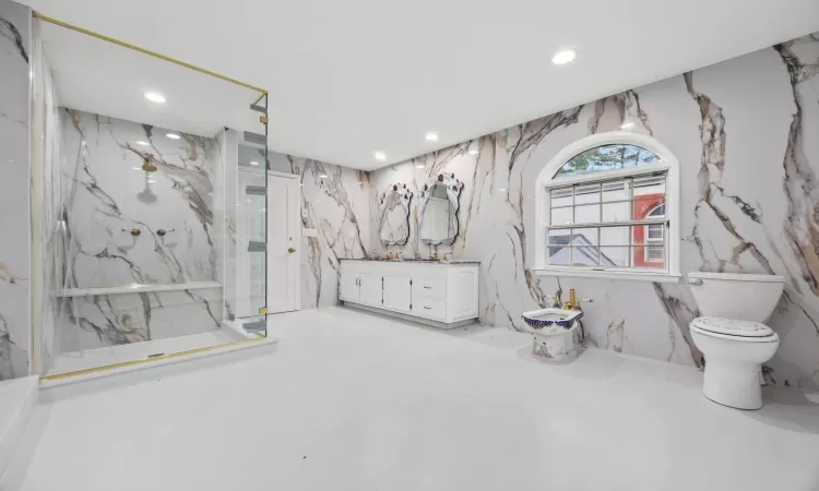 Bathroom with toilet, walk in shower, a bidet, vanity, and tile walls