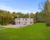 Rear view of house featuring a balcony, a patio, french doors, and a lawn