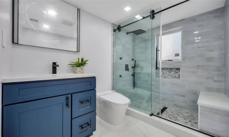 Bathroom with vanity, toilet, and a shower with shower door