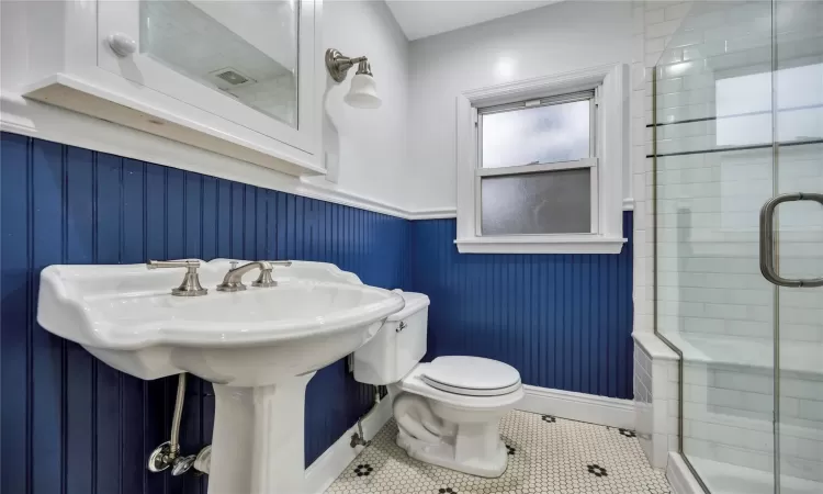 Bathroom with tile patterned flooring, a shower with shower door, and toilet