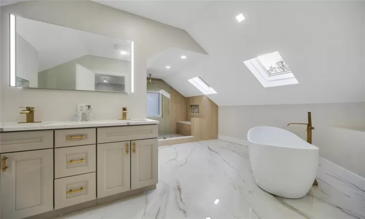 Bathroom featuring separate shower and tub, wooden walls, vaulted ceiling with skylight, and vanity