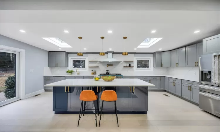 Kitchen with a skylight, tasteful backsplash, stainless steel refrigerator with ice dispenser, pendant lighting, and a kitchen island