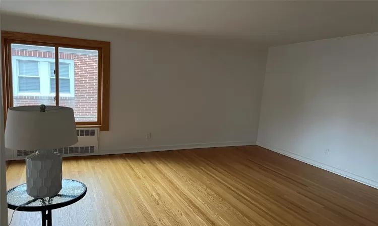 Spare room with light hardwood / wood-style floors and radiator heating unit