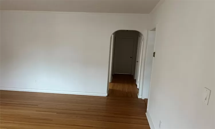 Empty room with hardwood / wood-style floors and crown molding