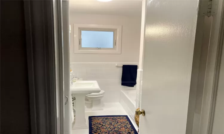 Bathroom featuring tile walls and toilet