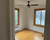 Empty room with ceiling fan, light wood-type flooring, radiator heating unit, and a wealth of natural light