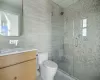 Bathroom featuring tile walls, an enclosed shower, vanity, and toilet