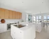 Kitchen featuring white cabinetry, kitchen peninsula, a kitchen island, black electric stovetop, and pendant lighting