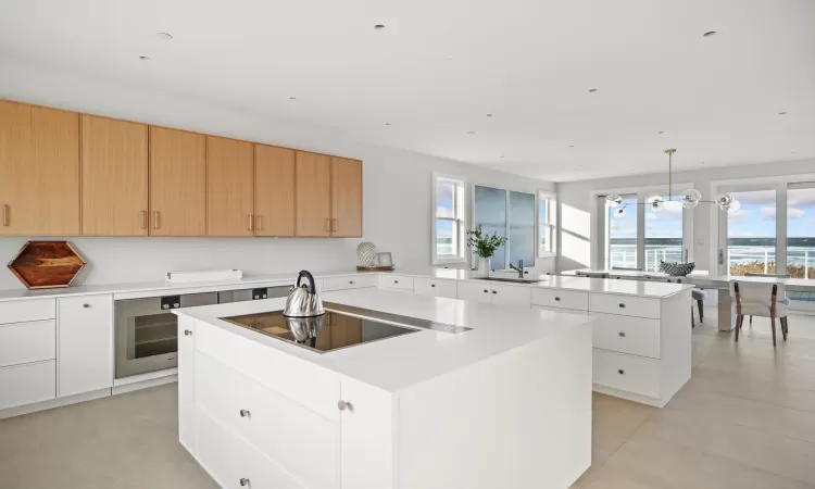 Kitchen featuring white cabinetry, kitchen peninsula, a kitchen island, black electric stovetop, and pendant lighting