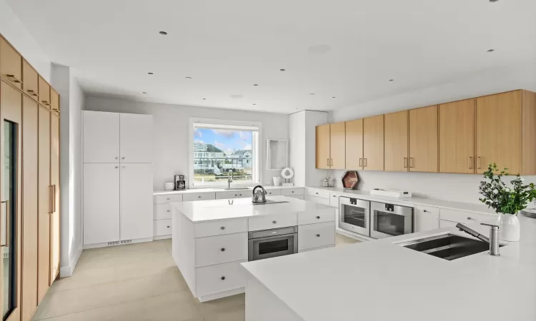 Kitchen featuring sink, a center island, wall oven, and white cabinetry