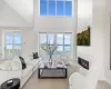 Living room featuring a towering ceiling, a high end fireplace, and a water view