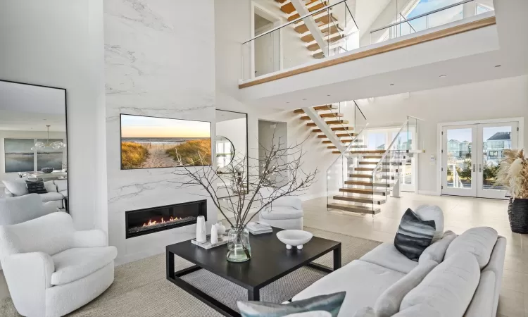 Living room featuring a towering ceiling, french doors, and a premium fireplace