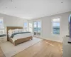 Bedroom with light hardwood / wood-style flooring, a water view, multiple windows, and access to exterior