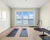 Exercise area with a healthy amount of sunlight, a water view, and hardwood / wood-style floors