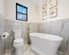 Bathroom with tile walls, a bath, and toilet