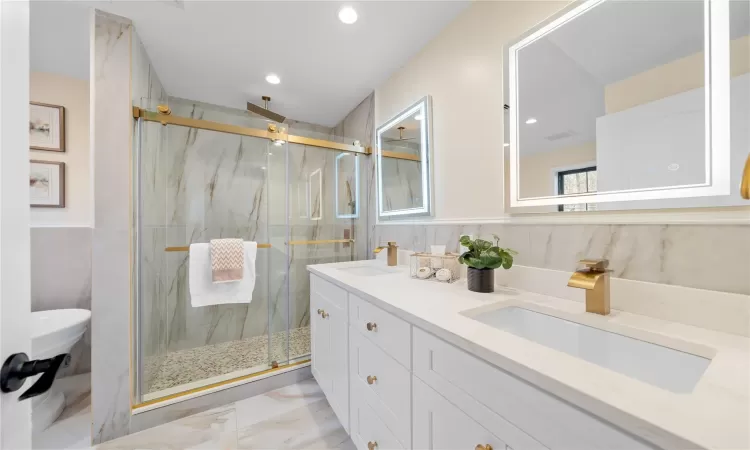 Bathroom with tile walls, an enclosed shower, and vanity