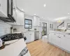 Kitchen with stainless steel appliances, white cabinets, sink, and light wood-type flooring