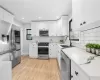 Kitchen with sink, white cabinetry, light hardwood / wood-style floors, decorative backsplash, and appliances with stainless steel finishes