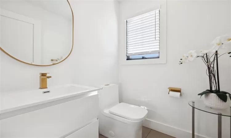 Bathroom with toilet, vanity, and tile patterned flooring