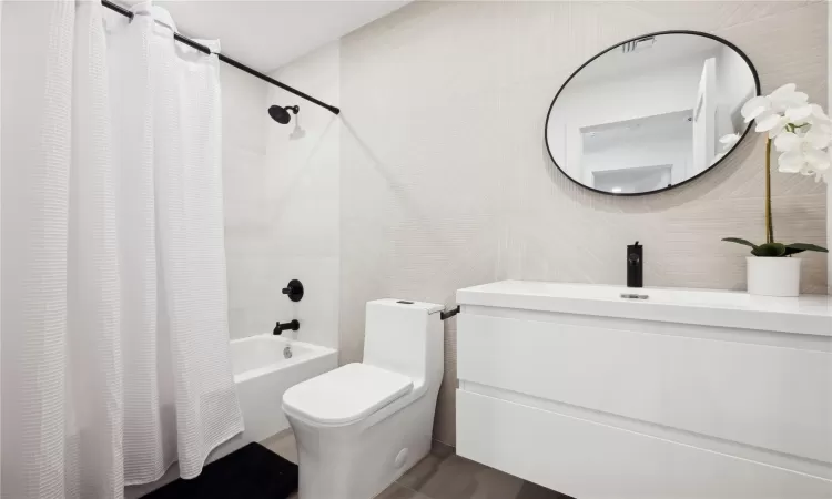 Full bathroom with sink, toilet, tile walls, and shower / tub combo with curtain