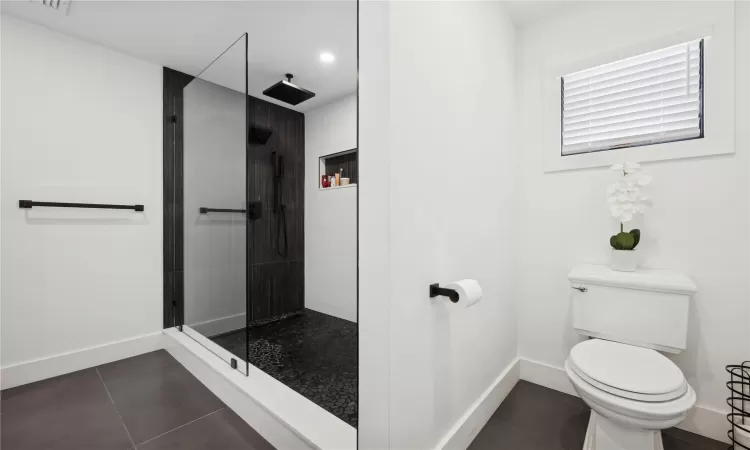 Bathroom with toilet, a shower, and tile patterned floors