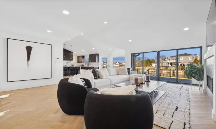 Living room with floor to ceiling windows, vaulted ceiling, and light parquet floors