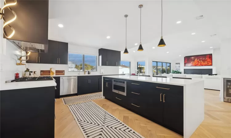 Kitchen with a kitchen island, a wealth of natural light, hanging light fixtures, and appliances with stainless steel finishes