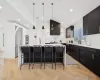 Kitchen with light parquet floors, pendant lighting, a center island, a breakfast bar area, and sink