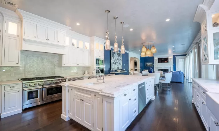 Kitchen with stainless steel appliances, white cabinets, sink, and hanging light fixtures