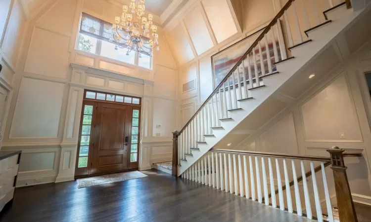 Entrance foyer with a wealth of natural light, crown molding, a towering ceiling, and a chandelier