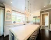 Kitchen with stainless steel built in refrigerator, a center island with sink, white cabinets, and pendant lighting