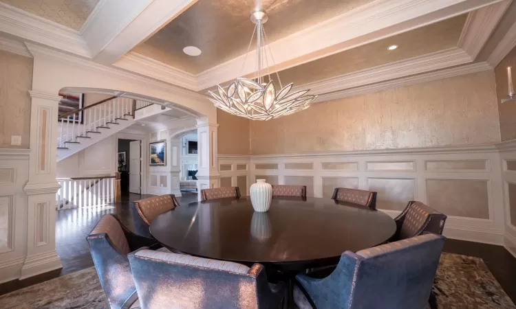 Dining area featuring beamed ceiling, an inviting chandelier, ornamental molding, and dark hardwood / wood-style flooring