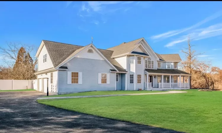 View of front of house with a garage, a porch, and a front lawn