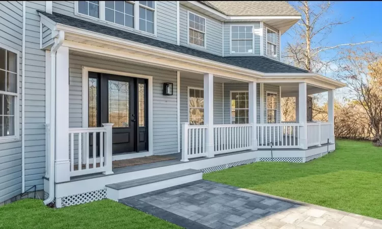 Doorway to property featuring a yard and covered porch