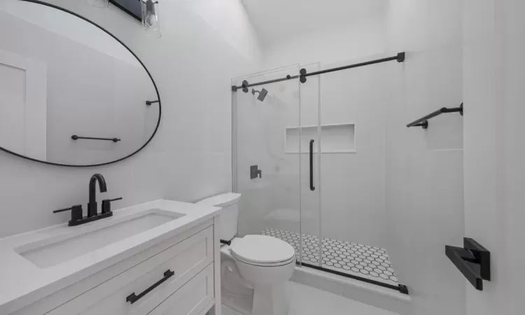 Bathroom featuring tile walls, a shower with shower door, vanity, and toilet