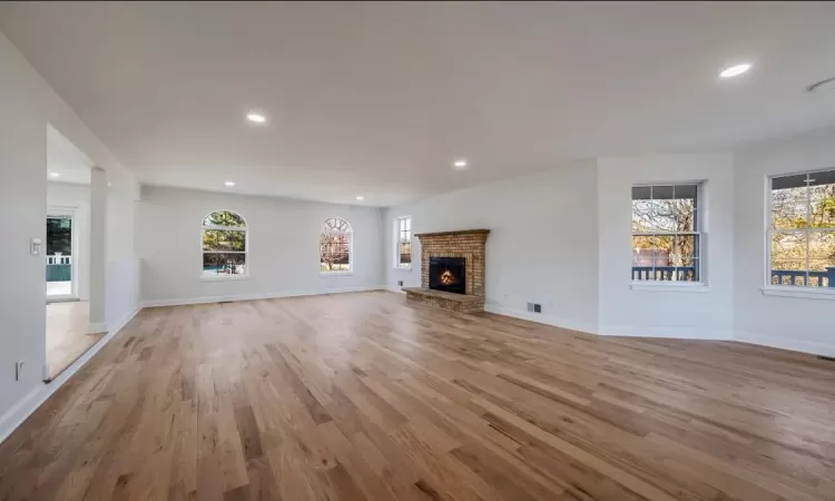 Unfurnished living room with light hardwood / wood-style flooring and a brick fireplace