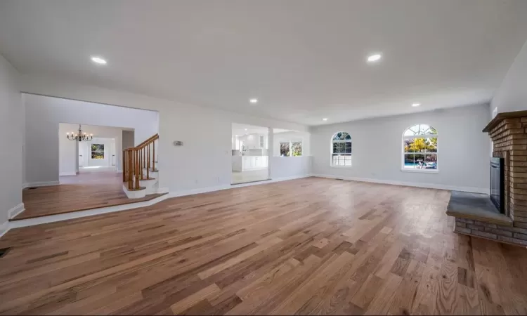 Unfurnished living room with a fireplace, a notable chandelier, and hardwood / wood-style floors