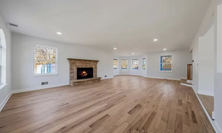 Unfurnished living room with light hardwood / wood-style floors, a wealth of natural light, and a fireplace