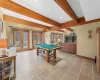 Playroom featuring french doors, beam ceiling, a healthy amount of sunlight, and pool table which leads to the stone fireplace, built in bookshelves