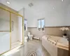 Bathroom with toilet, a bidet, tile walls, a baseboard heating unit, and independent shower and bath