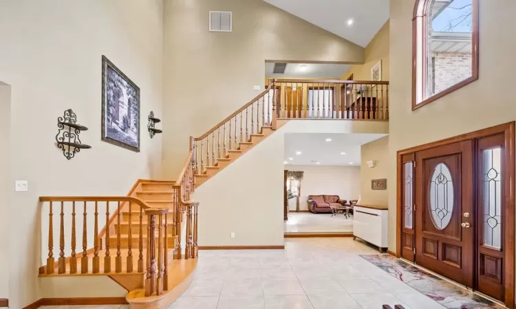 Entryway with high vaulted ceiling and light tile patterned flooring