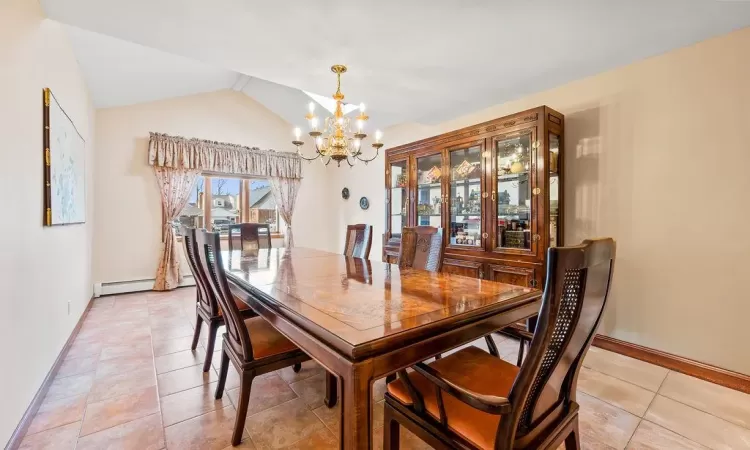 Tiled dining room with lofted ceiling, a baseboard heating unit, and a chandelier