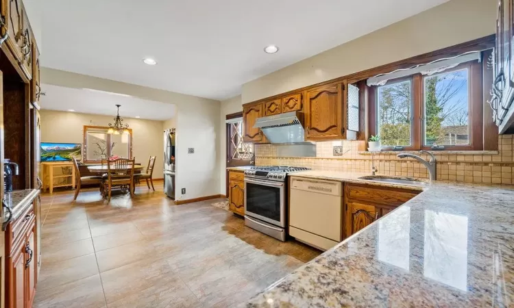 Kitchen featuring sink, decorative light fixtures, backsplash, and appliances with stainless steel finishes