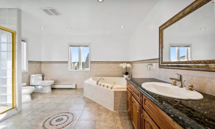 Bathroom featuring a tub to relax in, tile walls, baseboard heating, and a wealth of natural light