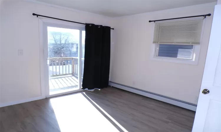 Primary Bedroom with baseboard heating, ornamental molding, and dark hardwood / wood-style flooring